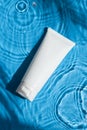 Plastic white tube for cream or lotion on beautiful burst and glare. Skincare or sunscreen cosmetic on blue background