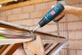 Plastic window installation. Worker attaches anchor plate with screwdriver.