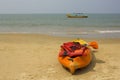 Plastic yellow-orange kayak with paddles and red life vests, stands on a sandy beach against the background of the sea and a large