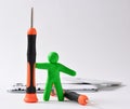 a plasticine figurine of a man holds a screwdriver upright. disassembled smartphone in the background. technology repair concept, Royalty Free Stock Photo