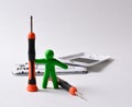 a plasticine figurine of a man holds a screwdriver upright. disassembled smartphone in the background. technology repair concept, Royalty Free Stock Photo
