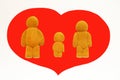 plasticine figurines of a man a woman and a child on the background of a red heart