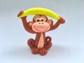 Cute colorful monkey is lifting yellow banana on his head cartoon made from clay on white background in healthy concept Royalty Free Stock Photo