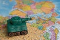 A plasticine tank on the background of a world map, as a symbol of peace and goodness. There is no war appeal. Stop war