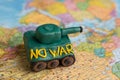 A plasticine tank on the background of a world map, as a symbol of peace and goodness. There is no war appeal. Stop war