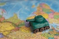 A plasticine tank on the background of a world map, as a symbol of peace and goodness. There is no war appeal. Stop war