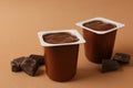 Plastics cups of chocolate yogurt on brown background