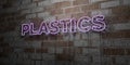 PLASTICS - Glowing Neon Sign on stonework wall - 3D rendered royalty free stock illustration