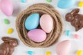 Pink, blue, and purple Easter eggs in nest with chocolate rabbits and jellybeans