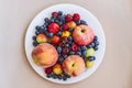 A plate of appetizing ripe juicy sweet fruit and berries: peaches, apples, plums, cherry plums, raspberries, blueberries,cherries. Royalty Free Stock Photo