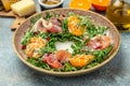 plate of arugula salad with mandarins, prosciutto jamon and Parmesan cheese on a light background. banner, menu, recipe place for Royalty Free Stock Photo