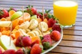 plate with assortment of fruit slices on a wooden table and glass with fresh orange juice healt Royalty Free Stock Photo