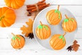 Plate of autumn pumpkin cupcakes on a white wood background