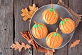 Plate of autumn pumpkin cupcakes on a rustic wood background