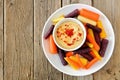 Plate of baby rainbow carrots with hummus on rustic wood