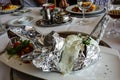 Plate with a baked potato artfully wrapped in aluminum foil with herb quark . Potato swan figure typical german meal in