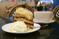 Plate of banoffee pie cake and whipped cream with blurry coffee cup in background Royalty Free Stock Photo