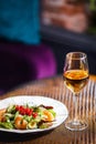 A plate with a beautiful appetizing salad of fresh vegetables, shrimps, quail eggs and lingonberries is on the table with a wine Royalty Free Stock Photo