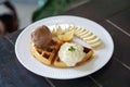A plate of Belgian waffle with banana and caramel sauce, topped with whipped cream and ice cream Royalty Free Stock Photo