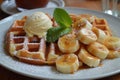 A plate of Belgian waffles, paired with a scoop of vanilla ice cream and caramelized bananas. Royalty Free Stock Photo