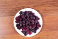 Plate with black sweet blackberry covered with ice on a wooden background. Stocking up for winter from frozen berries. Royalty Free Stock Photo