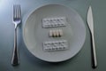 plate with blister packs and medicine pills, fork and knife - concept for food problems, drug abuse, chemical feeding Royalty Free Stock Photo