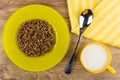 Plate with boiled buckwheat, spoon, yellow napkin, cup of milk