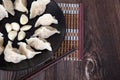 A plate of boiled dumplings, a few pieces of peeled garlic and chopsticks beside the plate