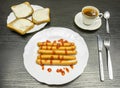 A plate of boiled sausages with ketchup, sandwiches with dark brown bread with butter and a cup of brewed tea from the bag.