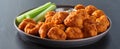 Plate of boneless chicken wings with buffalo sauce and celery sticks