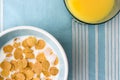 Plate of breakfast cereal and glass of orange juice on table-clotch