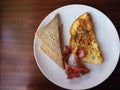 Plate of breakfast with omelet, bacon and toasts. Top view