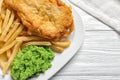 Plate with British traditional fish and potato chips on wooden background