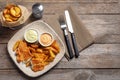 Plate with British traditional fish and potato chips on wooden background, top view. Royalty Free Stock Photo