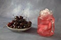 A plate with a bunch of ripe cherries and a glass of cherry juice with ice