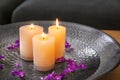 Plate with burning wax candles, water and flower petals on table Royalty Free Stock Photo