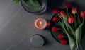 a plate with a candle and some red tulips