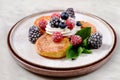 Plate with cheese cakes and berries, mint, merble table