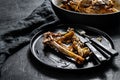 A plate of chicken bones and a chicken skeleton in a baking dish. Leftovers from dinner. Black background. Top view