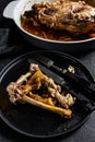 A plate of chicken bones and a chicken skeleton in a baking dish. Leftovers from dinner. Black background. Top view