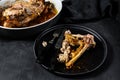 A plate of chicken bones and a chicken skeleton in a baking dish. Leftovers from dinner. Black background. Top view
