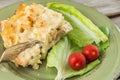 Plate of chicken lasagna with lettuce and cherry tomato