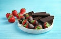 Plate with chocolate covered strawberries and bars on wooden table Royalty Free Stock Photo