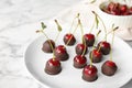 Plate of chocolate dipped cherries on marble table Royalty Free Stock Photo