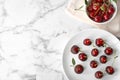 Plate of chocolate dipped cherries on white marble table, flat lay. Royalty Free Stock Photo