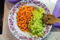 Plate with chopped frying carrots and green pepers as ingredients for vegetable stew.