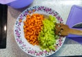 Plate with chopped frying carrots and green pepers as ingredients for vegetable stew.