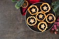 Plate of Christmas mincemeat tarts, overhead view table scene over a dark background.