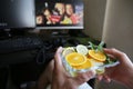 Plate of citrus fruits in their hands against the backdrop of monitors and a computer keyboard. Healthy food. Royalty Free Stock Photo