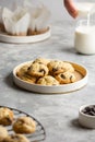 Plate with classic chocolate chip cookies on a concrete gray background with a glass of milk and muffins. Royalty Free Stock Photo